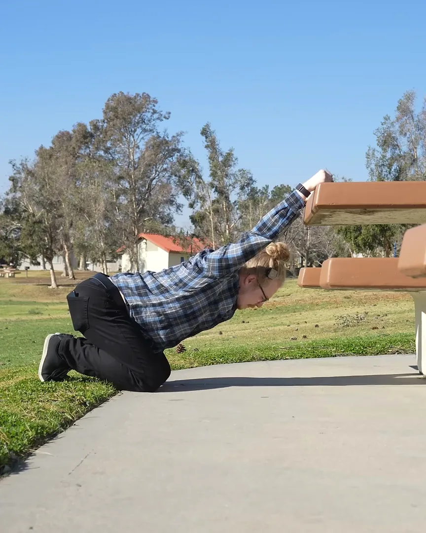 David kneeling with his arms on a bench, chest sinking into a deep shoulder stretch